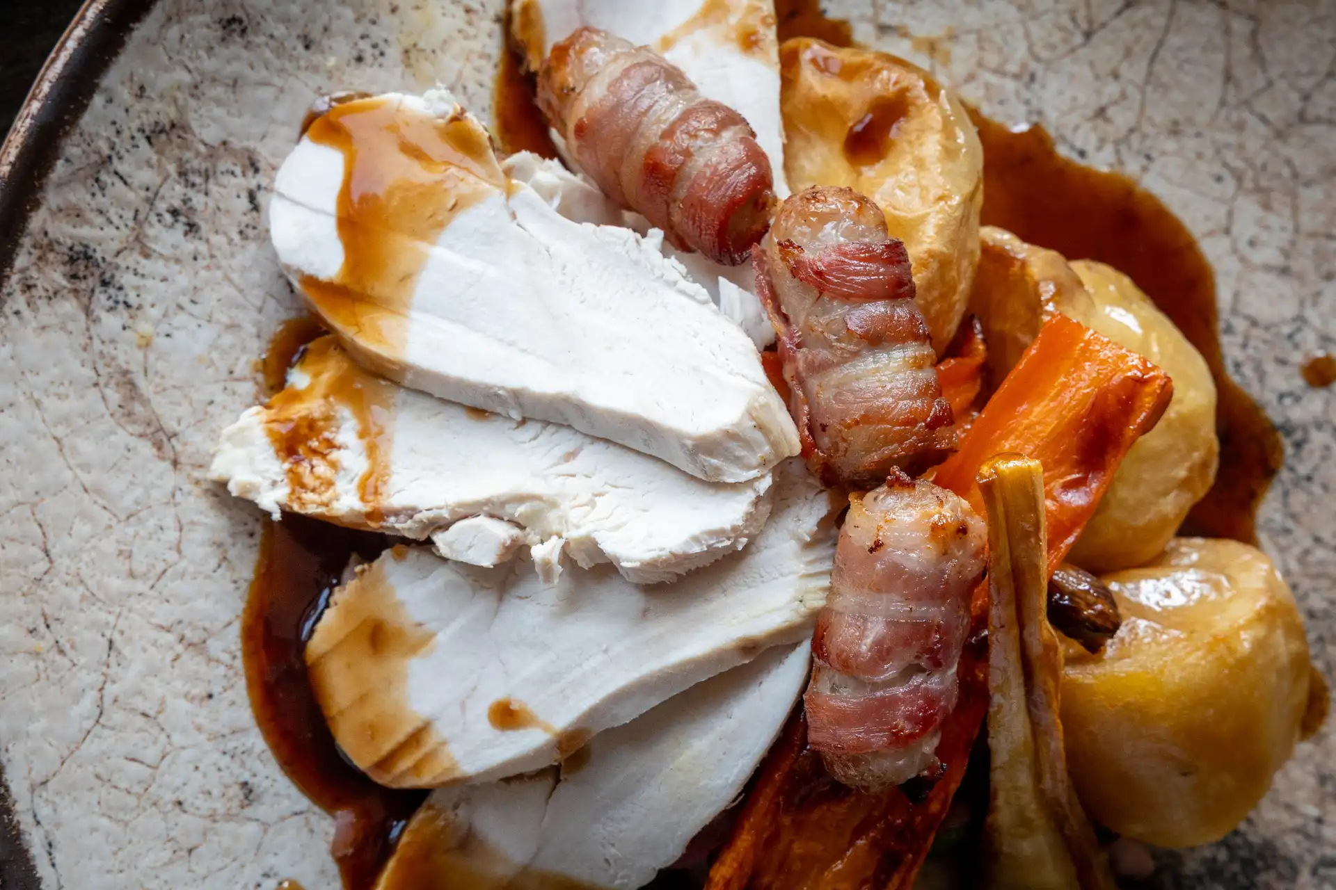 Close-up of sliced turkey with pigs in blankets, roast potatoes and gravy, at The Old Red Lion, Horseheath